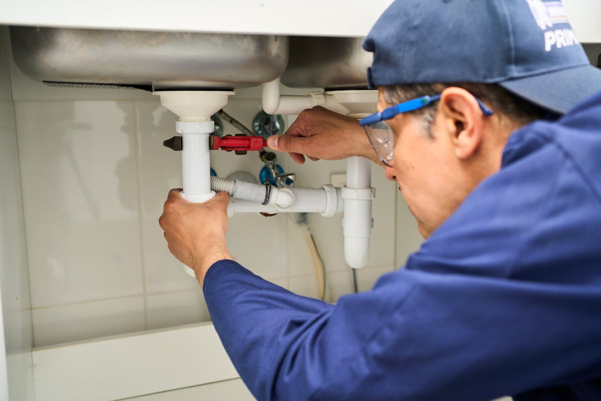 Plumber repairing pipes under a kitchen sink
